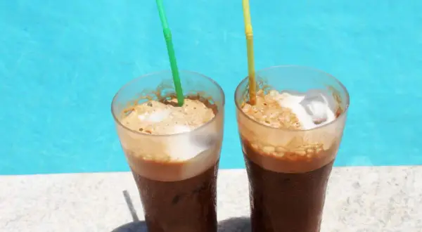Zwei erfrischende Cafe Frappe mit Eis und Schaum stehen am Poolrand.