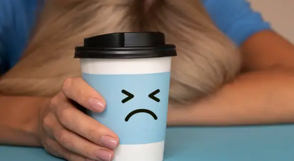Trauriger Kaffeebecher mit traurigem Gesicht, der die Nachteile von Kaffee symbolisiert.