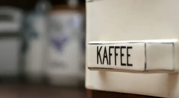 Ein Behälter mit der Aufschrift "KAFFEE" steht im Vordergrund. Im Hintergrund sind weitere Vorratsdosen zu sehen. Man fragt sich, ob Kaffee schlecht werden kann.