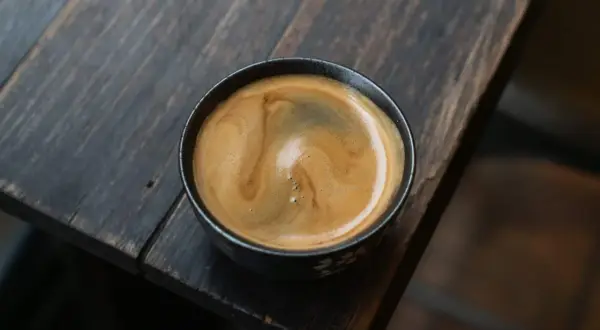 Ein cremiger **white americano** mit schöner Crema auf einem rustikalen Holztisch.