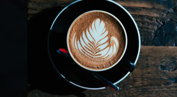 Ein Milchkaffee oder Cappuccino mit Latte Art auf einem Holztisch.