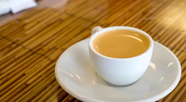 Eine Tasse Café Olé auf einem Unterteller, bereit zum Genuss auf einem Holztisch.
