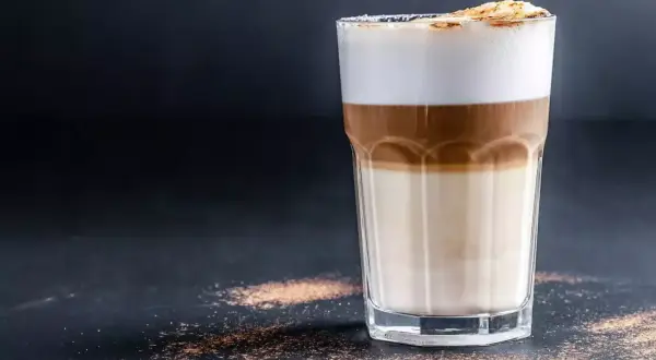 Ein Latte Macchiato mit drei Schichten: Milch, Espresso und Milchschaum, bestreut mit Zimt.