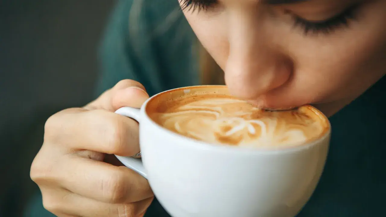 Eine Person trinkt genussvoll einen Latte Macchiato. Der warme Kaffee könnte ein kleiner Trost bei Gefühlen der Depression sein.