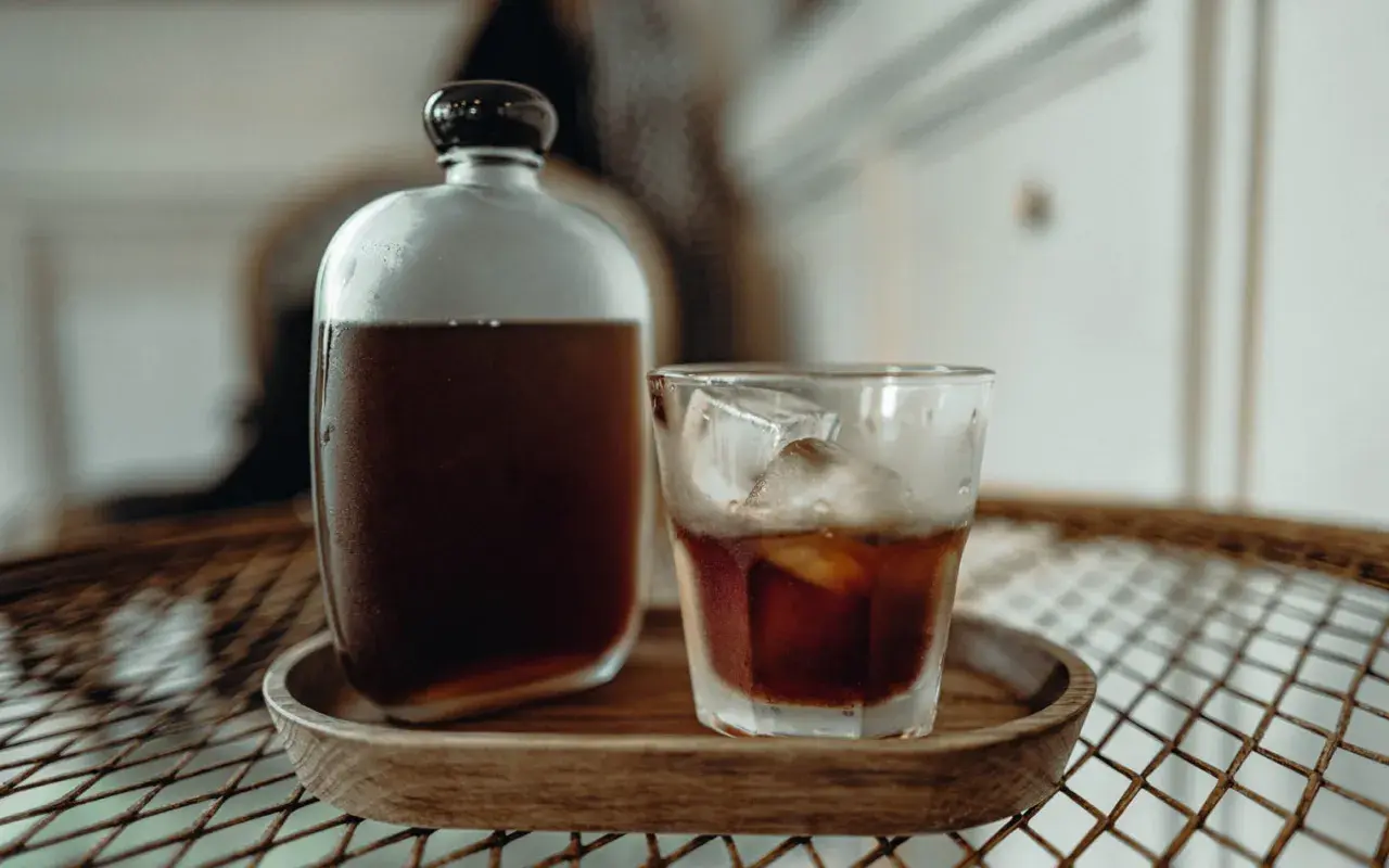 Kühl und erfrischend: Ein Glas Cold Brew mit Eiswürfeln neben einer Karaffe. Wie lange ziehen lassen für perfekten Geschmack?