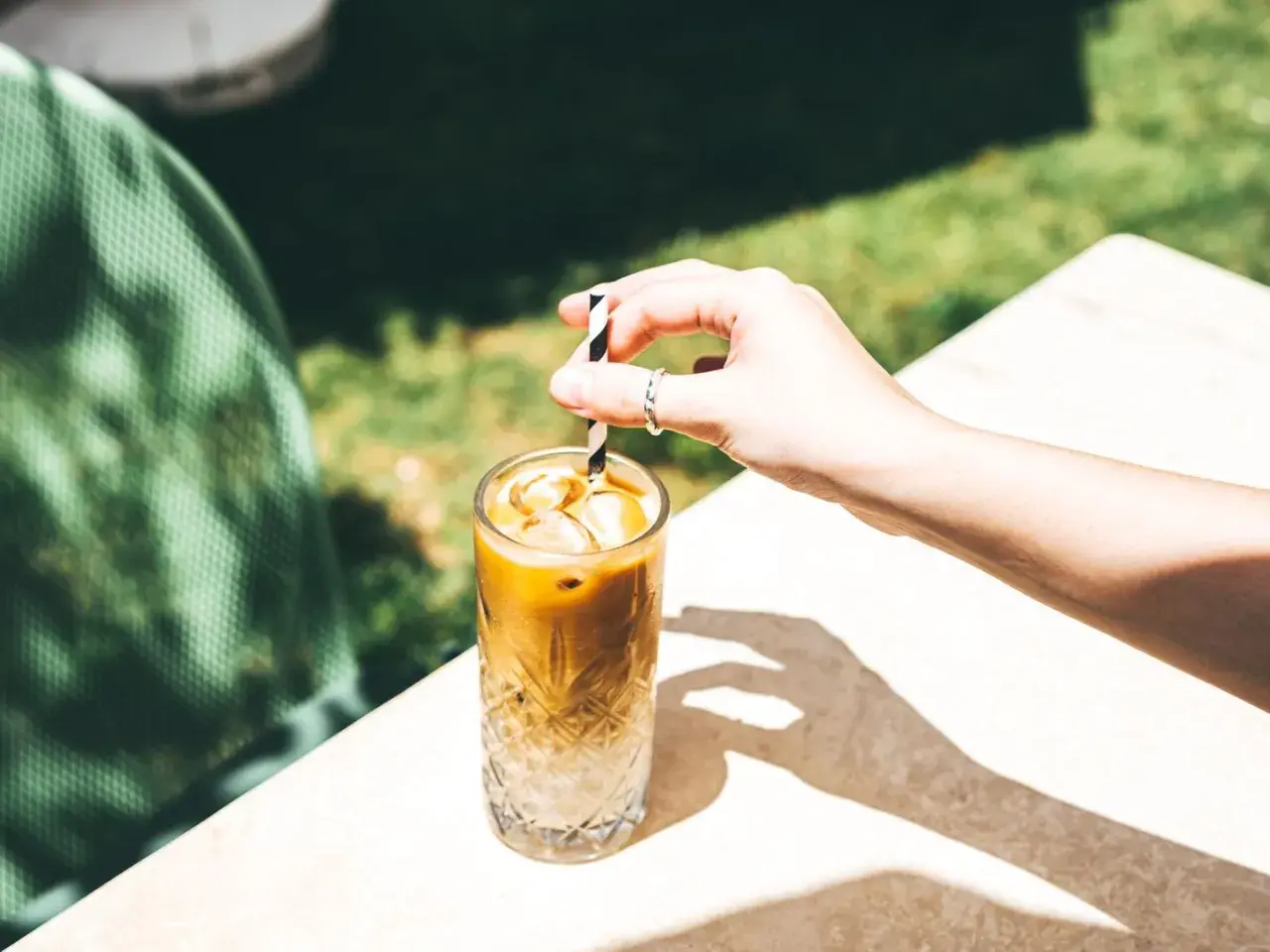 Erfrischender Eiskaffee ohne Eis, mit einem gestreiften Strohhalm, der in einem Glas mit Eiswürfeln steckt.