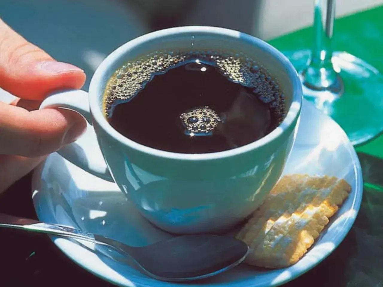 Eine Tasse schwarzer Kaffee mit Schaum, ein Keks und eine Löffel. So einfach ist, wie man schwarzen Kaffee macht.