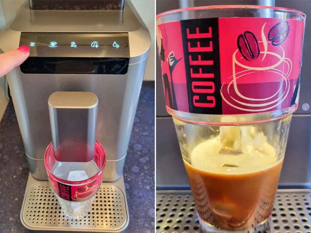 Eine Hand startet die Kaffeemaschine für einen erfrischenden cafe helado. Eiswürfel im Glas warten auf den heißen Espresso.