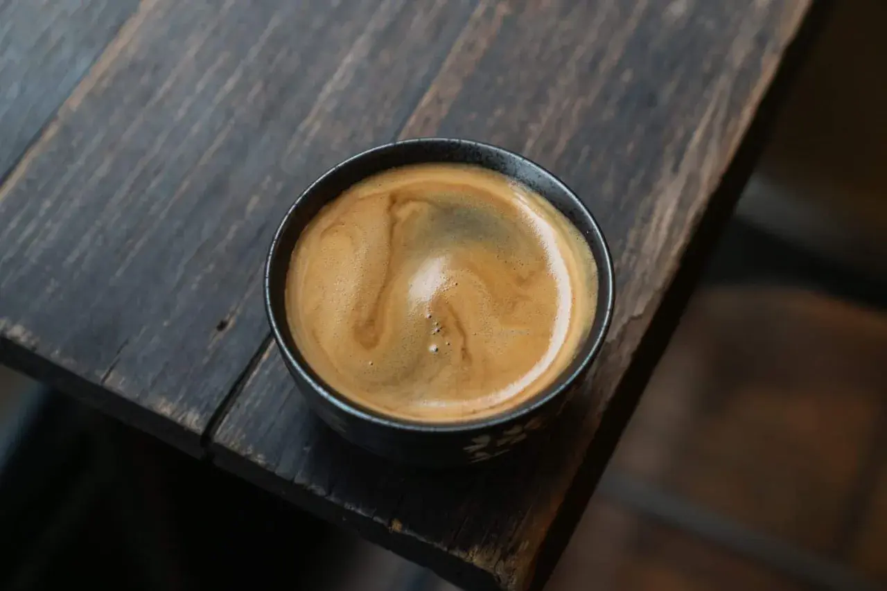 Ein cremiger **white americano** mit schöner Crema auf einem rustikalen Holztisch.