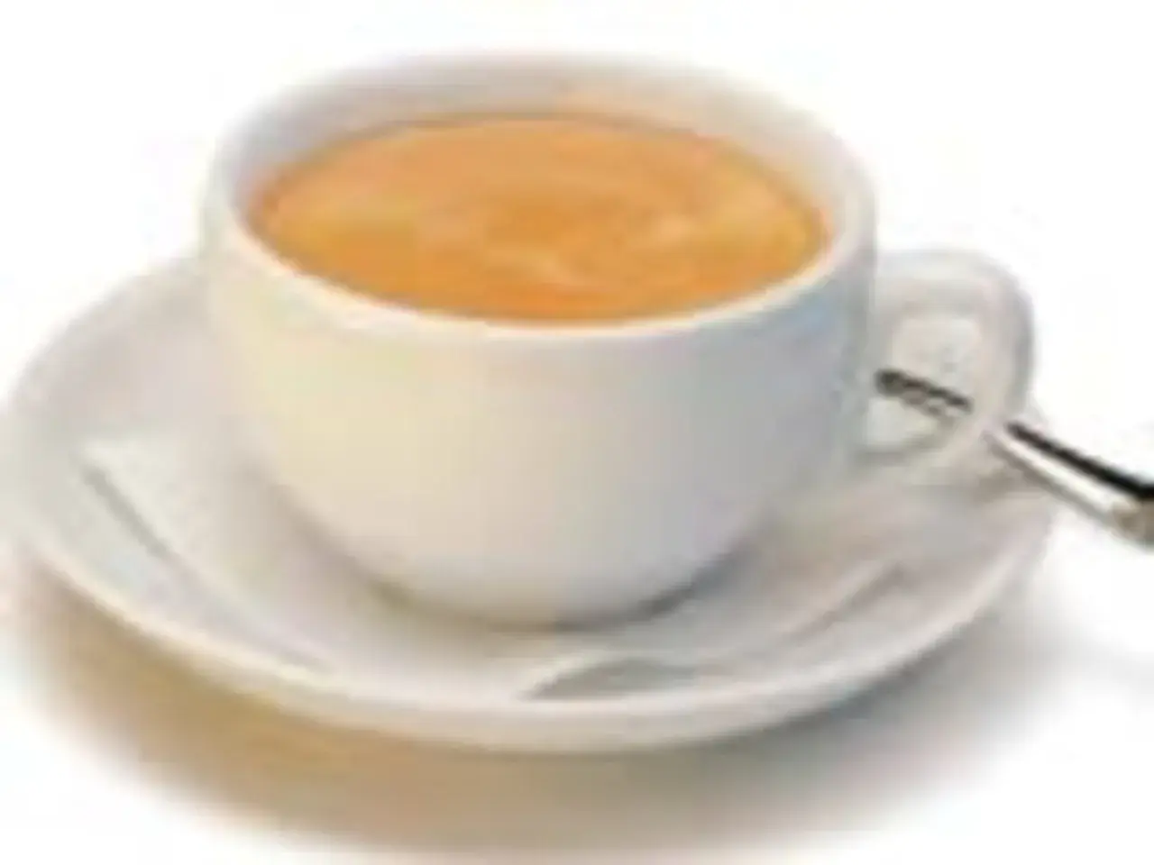 Eine Tasse mit cremigem, braunem Kaffee steht auf einer Untertasse. Ein kleiner Löffel liegt daneben.