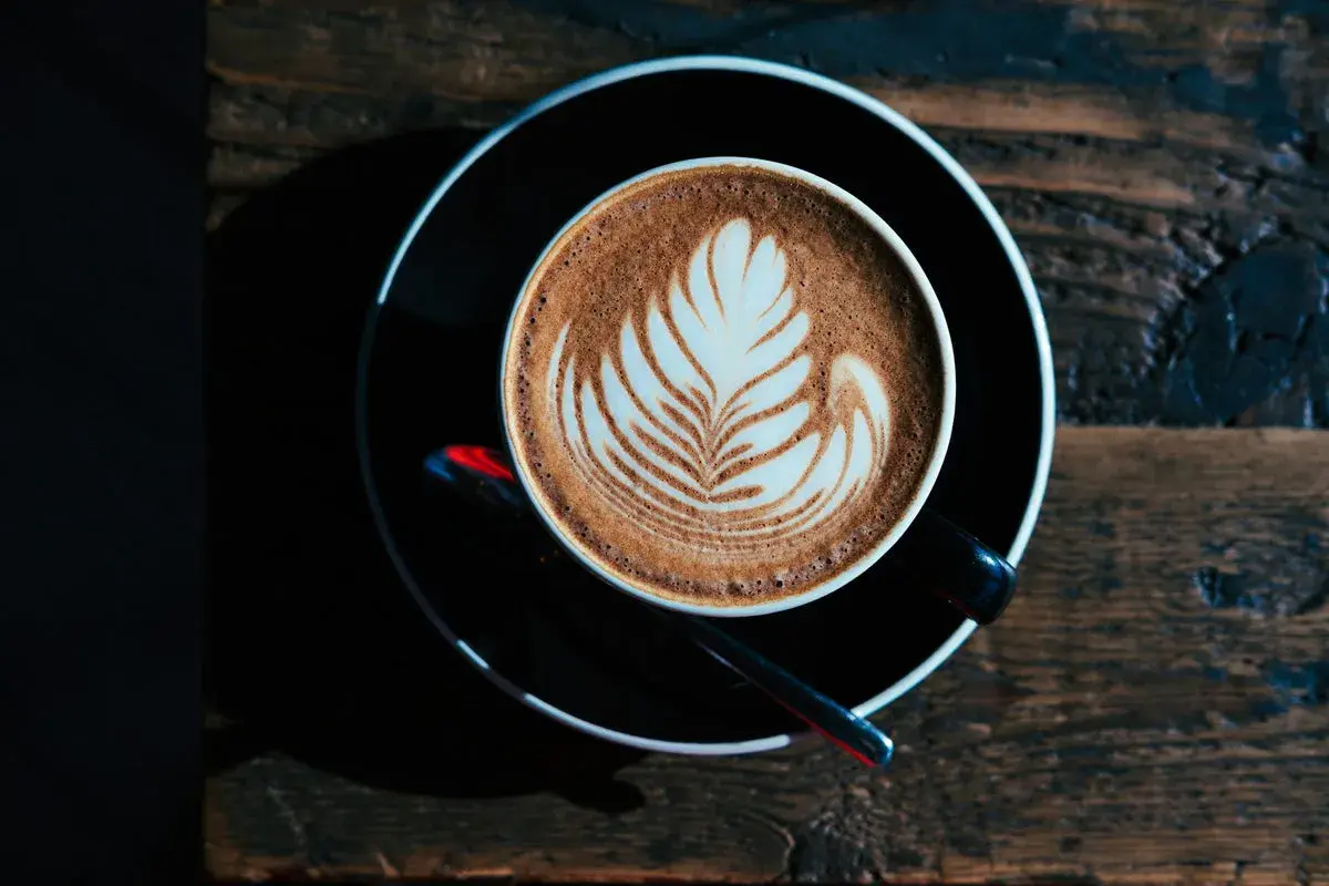 Ein Milchkaffee oder Cappuccino mit Latte Art auf einem Holztisch.