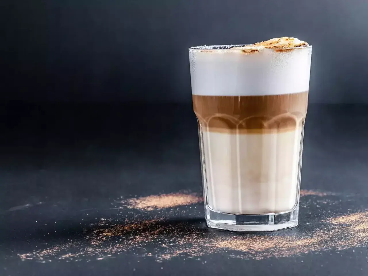 Ein Latte Macchiato mit drei Schichten: Milch, Espresso und Milchschaum, bestreut mit Zimt.