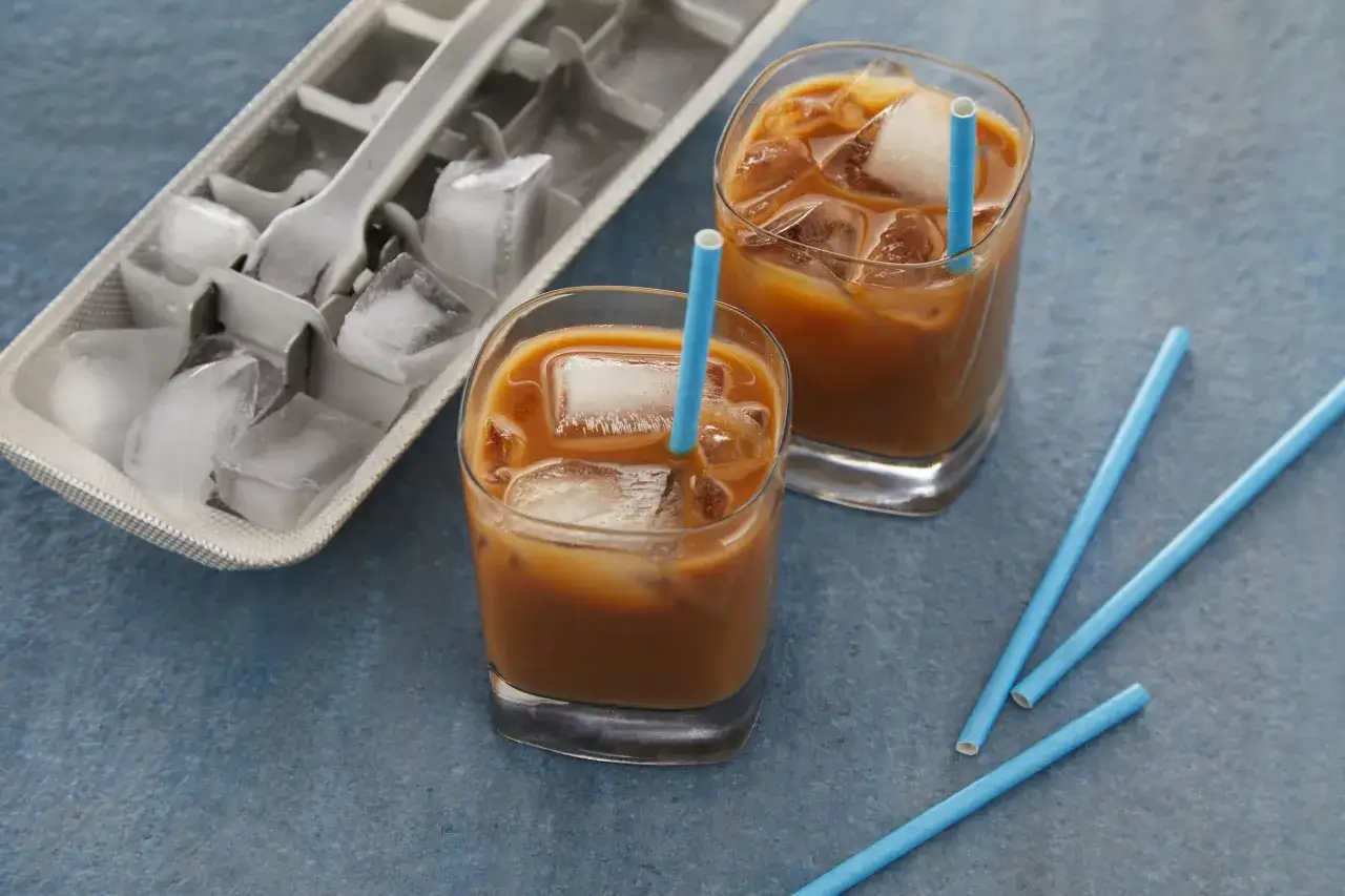 Zwei Gl&auml;ser Nespresso Iced Coffee mit Eisw&uuml;rfeln und blauen Strohhalmen, daneben eine Eisw&uuml;rfelform.