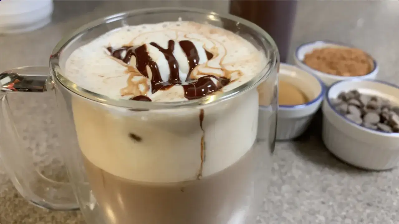 Ein k&ouml;stlicher Caff&egrave; Mocha mit Sahne und Schokoladensirup. Zutaten f&uuml;r Caff&egrave; Mocha Rezepte sind im Hintergrund zu sehen.