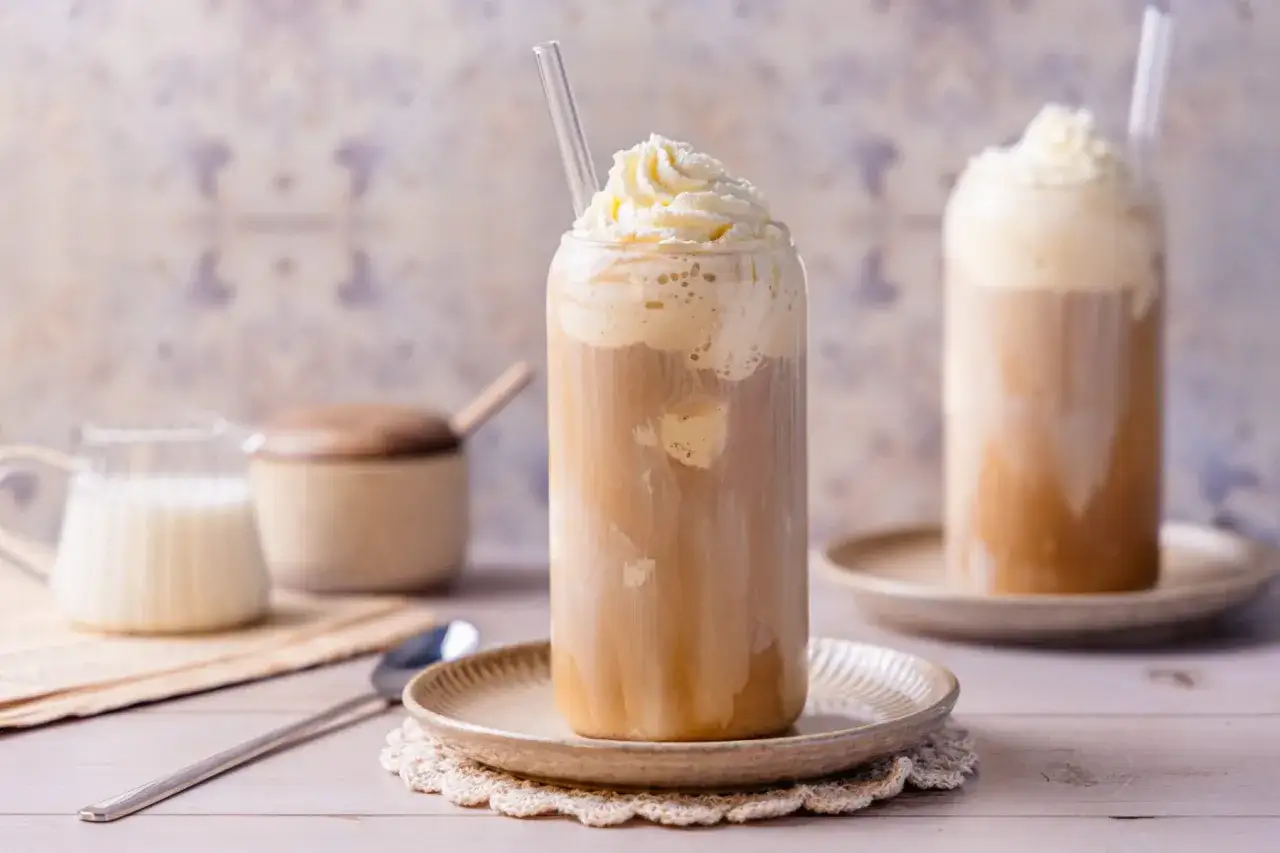 Ein erfrischender Eiskaffee mit Sahnehaube und Strohhalm. Perfekt für heiße Tage.