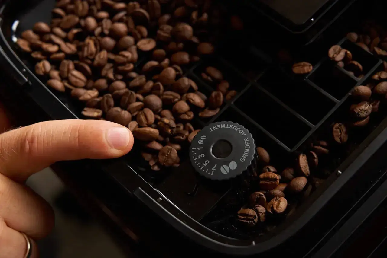 Finger stellt Mahlgrad ein, um zu verhindern, dass der Kaffee aus dem Vollautomaten sauer schmeckt.