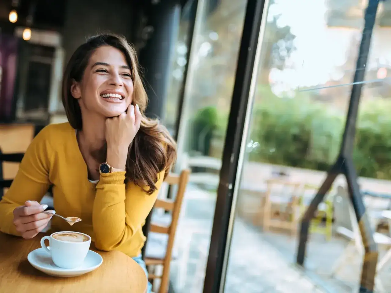 Frau lacht mit Kaffee, vielleicht wegen Kreislaufproblemen nach Kaffee.