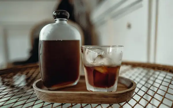 Kühl und erfrischend: Ein Glas Cold Brew mit Eiswürfeln neben einer Karaffe. Wie lange ziehen lassen für perfekten Geschmack?