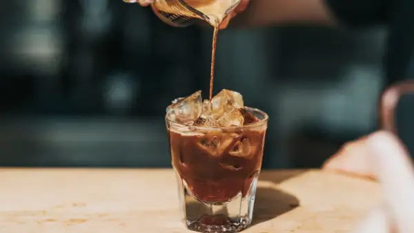 Ein Espresso wird in ein Glas mit Eis gegossen. Ist kalter Kaffee gesund? Diese erfrischende Zubereitung könnte die Antwort sein.