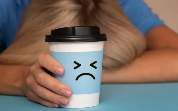Trauriger Kaffeebecher mit traurigem Gesicht, der die Nachteile von Kaffee symbolisiert.
