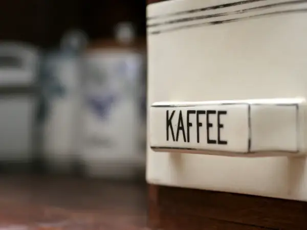 Ein Behälter mit der Aufschrift "KAFFEE" steht im Vordergrund. Im Hintergrund sind weitere Vorratsdosen zu sehen. Man fragt sich, ob Kaffee schlecht werden kann.