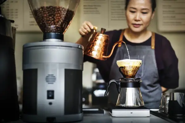 Barista bereitet mit einem Handfilter und einer Kupferkanne einen aromatischen Espresso zu.