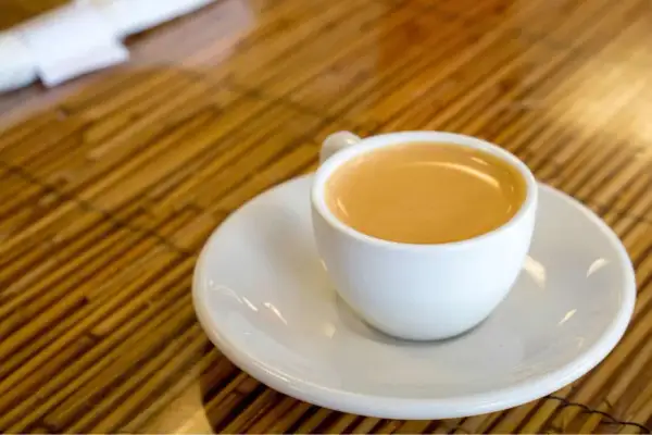 Eine Tasse Café Olé auf einem Unterteller, bereit zum Genuss auf einem Holztisch.