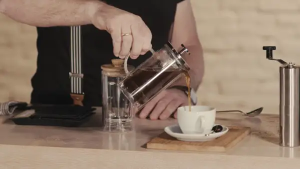 Mann gießt French Press Kaffee in eine Tasse. Die Menge ist für 2 Tassen ausgelegt.