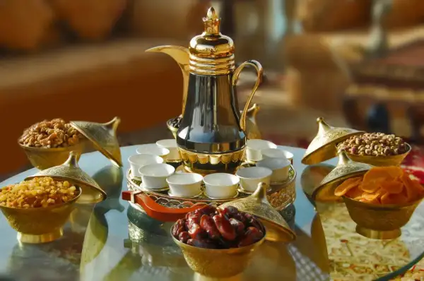 Elegante arabischer kaffee zubereitung mit Dallah, kleinen Tassen und Schalen voller Datteln, Nüssen und Trockenfrüchten.