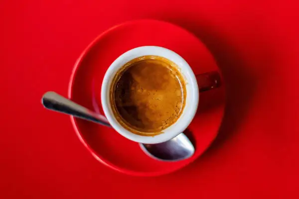 Eine Tasse Espresso auf rotem Untergrund. Die Wirkung von Espresso auf den Schlaf ist oft belebend, nicht schlaffördernd.